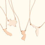 Four rose gold necklaces featuring distinct state-shaped pendants.