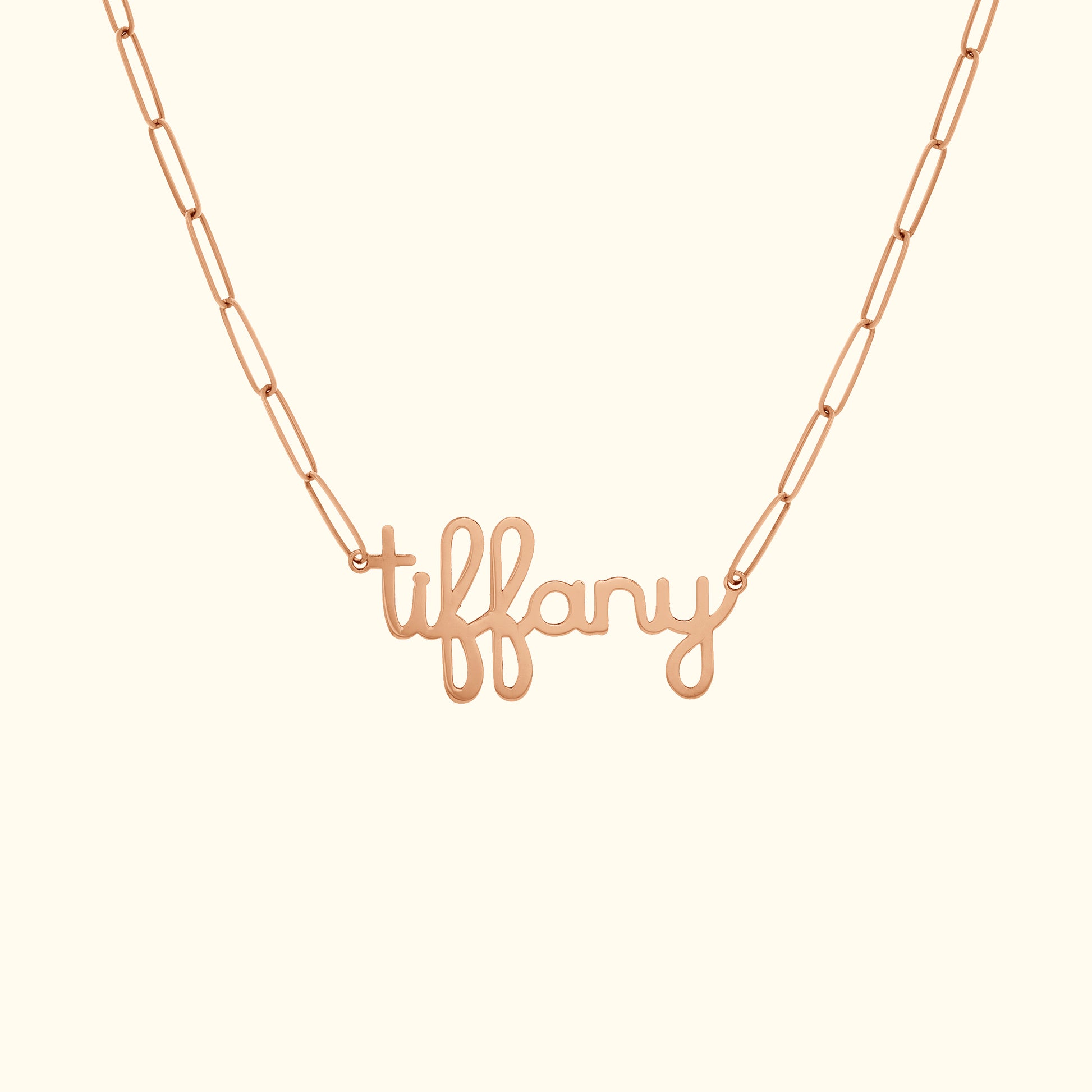 Rose gold necklace featuring a cursive "tiffany" pendant on a chain.