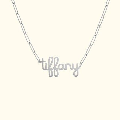 Silver necklace with "tiffany" in cursive letters on a chain.