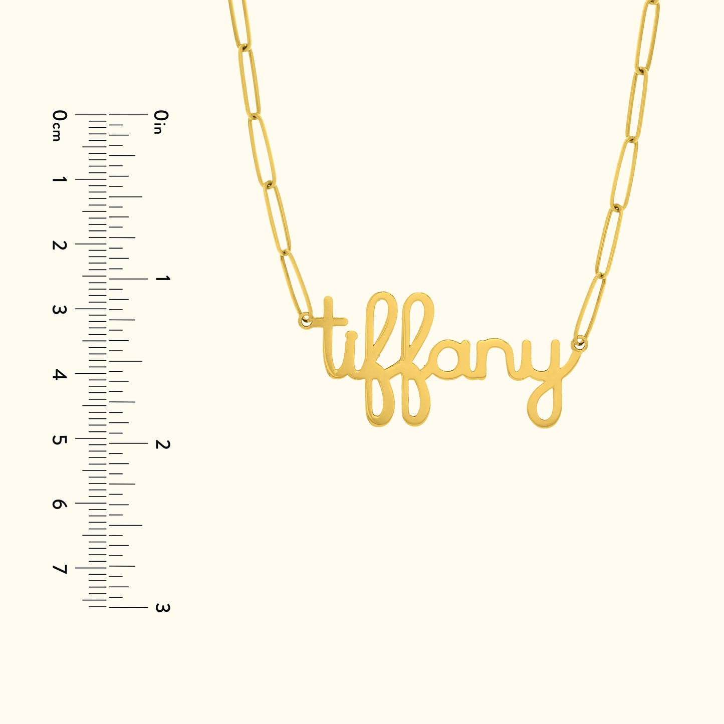 Gold necklace with the word "tiffany" in cursive lettering, alongside a ruler for size reference.