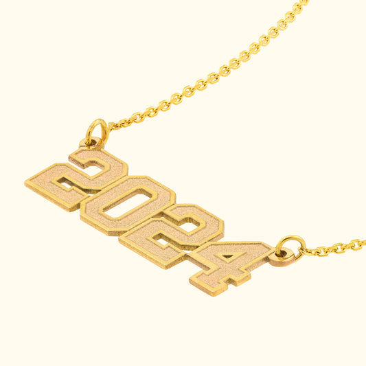 Gold necklace featuring the year "2024" in a bold, modern font.