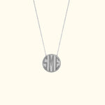 Monogrammed silver pendant necklace on a delicate chain.