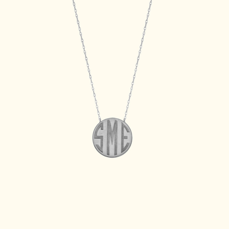 Monogrammed silver pendant necklace on a delicate chain.