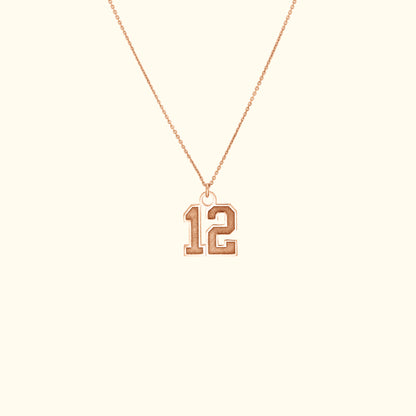 Rose gold necklace featuring a pendant shaped like the number 12.