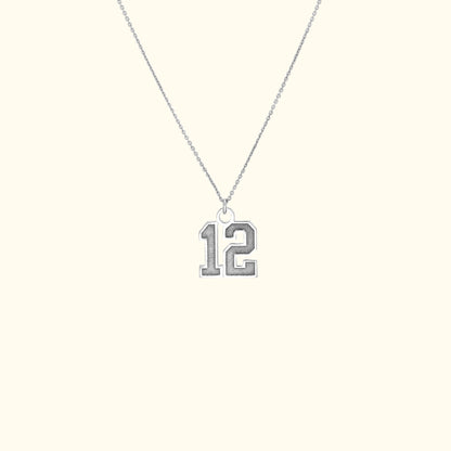 Silver necklace featuring a pendant with the number "12."