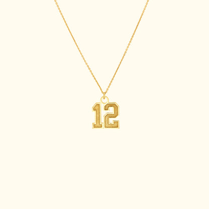 Gold necklace featuring a pendant with the number 12.