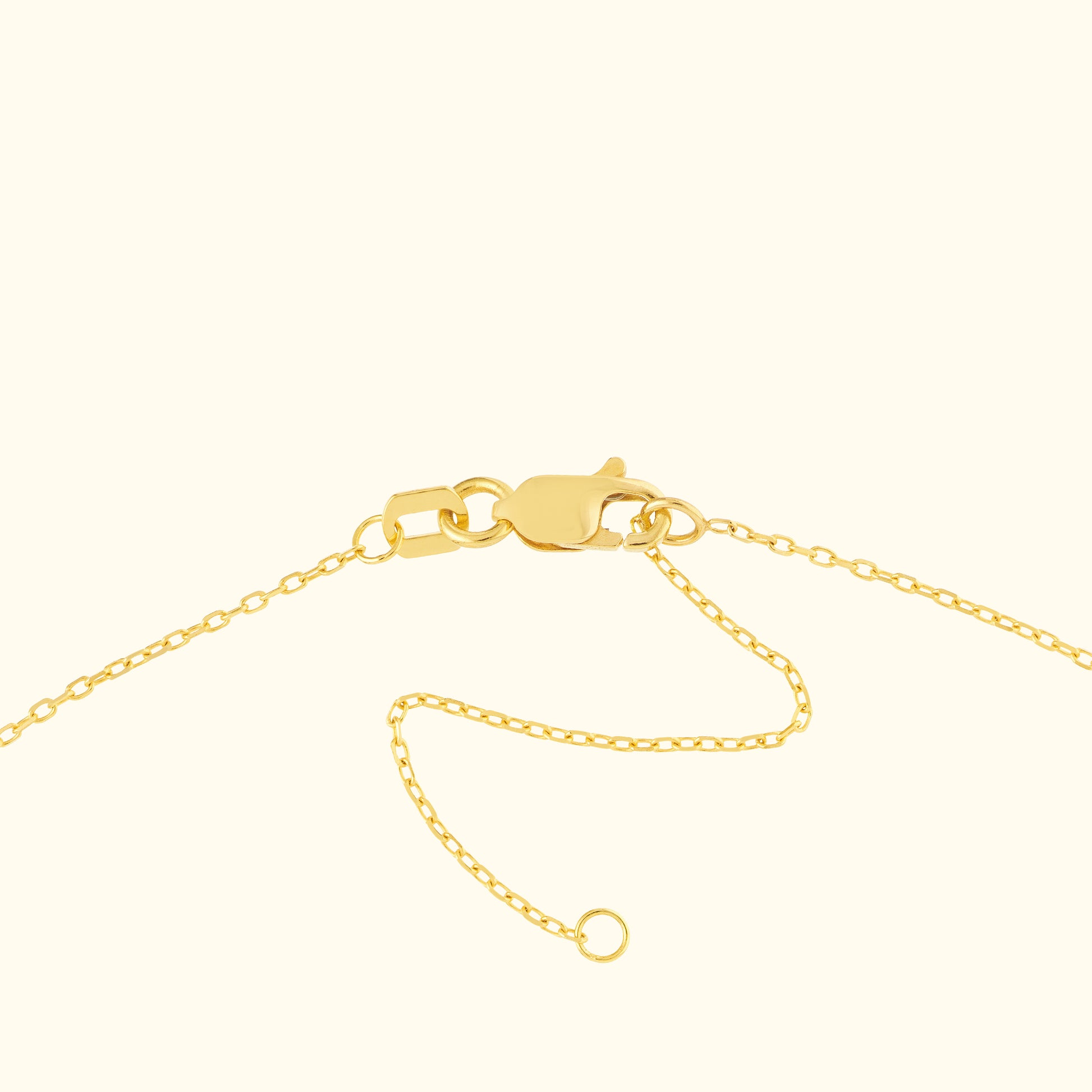 Close-up of a gold necklace clasp and chain against a light background.