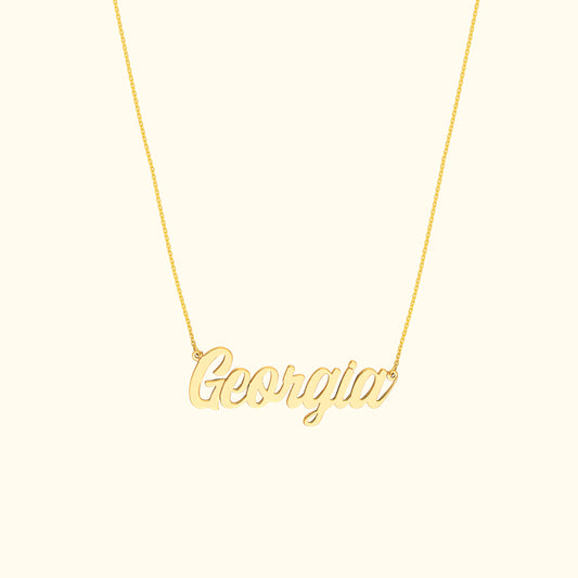 Gold necklace with a cursive name pendant reading "Georgia."