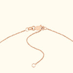Close-up of a delicate rose gold chain necklace with a clasp and adjustable links.