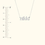 Silver name necklace spelling "nikki" with a simple chain against a light background.