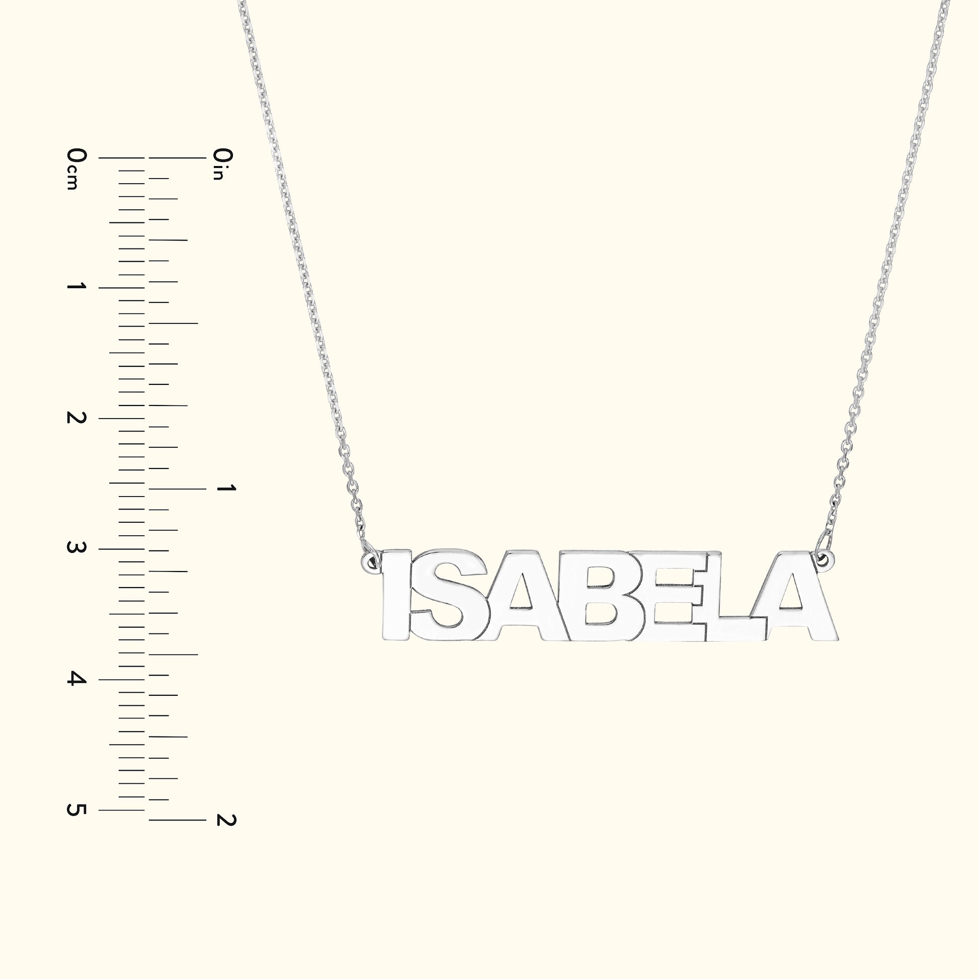 Silver name necklace spelling "ISABELA" with a ruler for size reference.