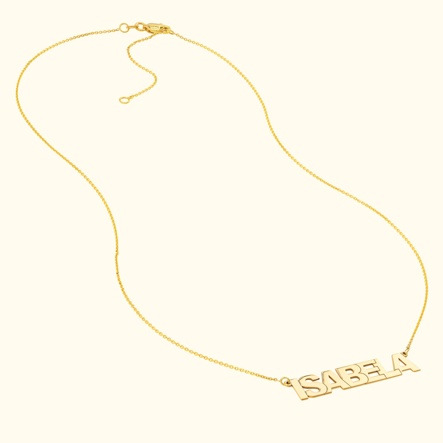 Gold name necklace with the word "ISABELA" in bold letters.