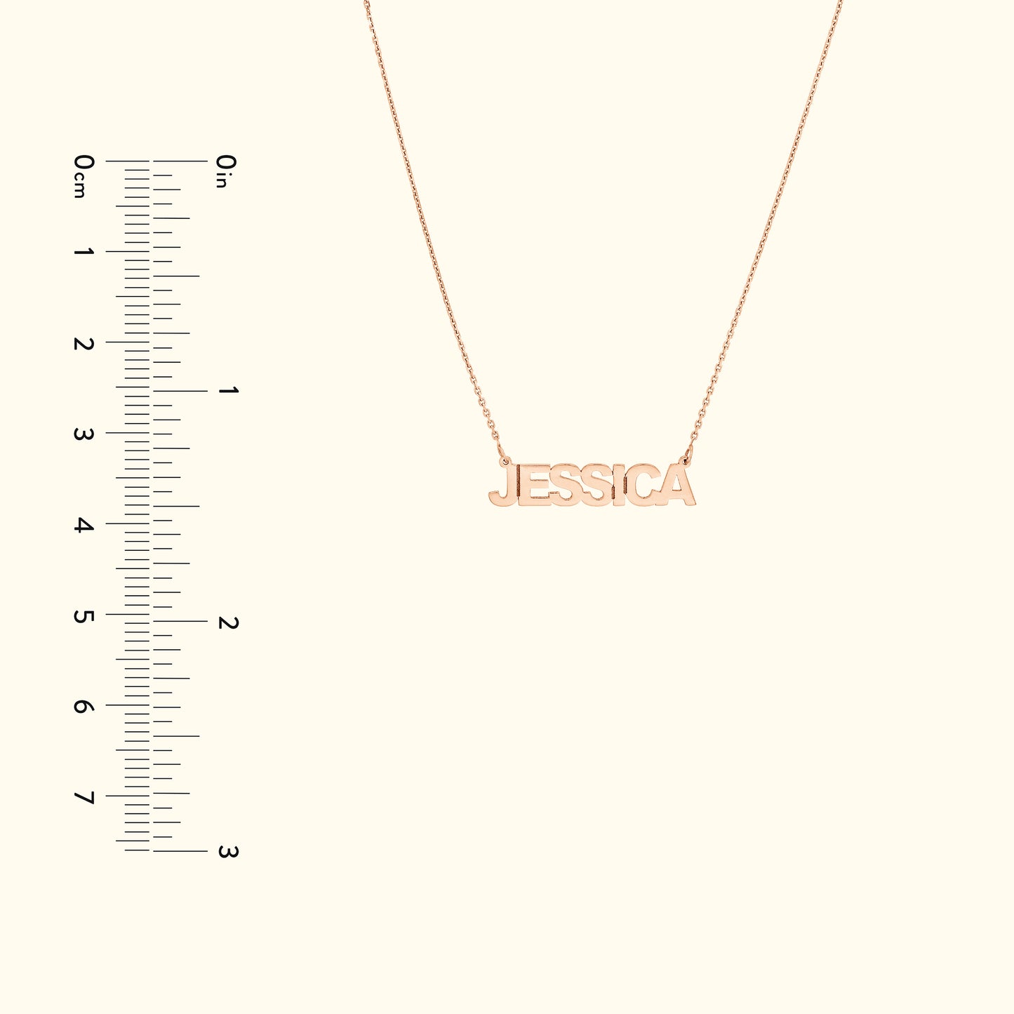 Gold name necklace spelling "JESSICA," displayed next to a measuring scale.