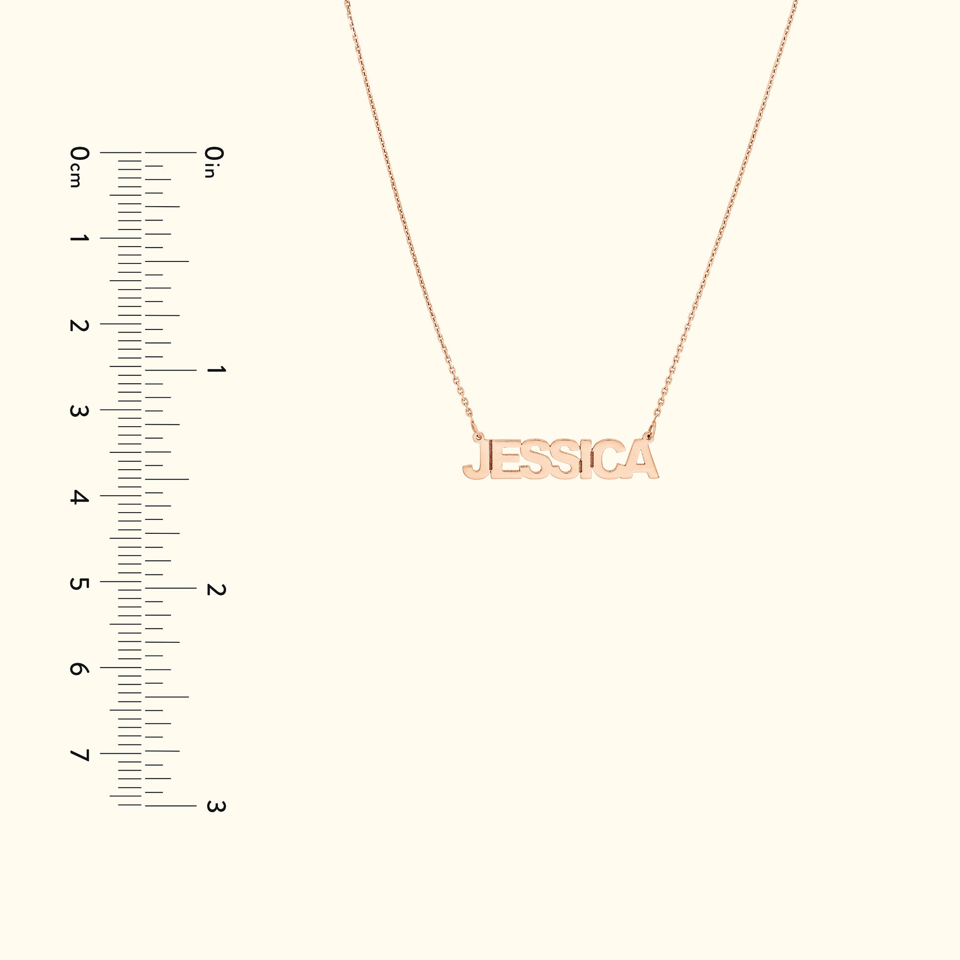 Gold name necklace spelling "JESSICA," displayed next to a measuring scale.