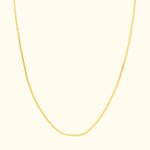 Delicate gold chain necklace with a smooth, subtle design against a light background.