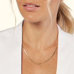 Delicate gold necklace resting on a woman's neck, with a subtle shimmer.