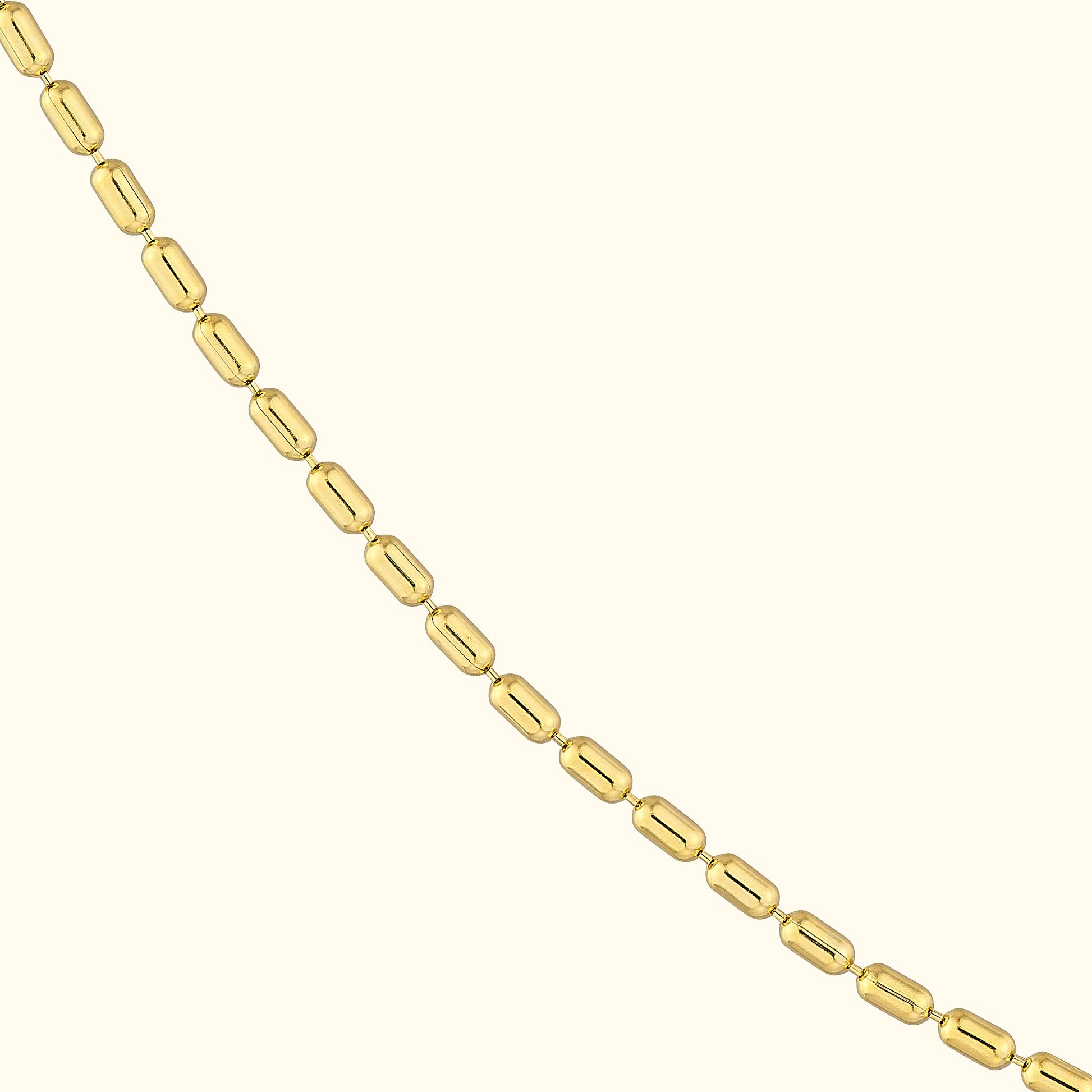 Gold elongated bead necklace on a light background.