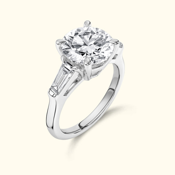 Solitaire diamond engagement ring with a round brilliant cut and tapered baguette accents.