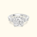 Three-stone engagement ring featuring a large round diamond center and tapered side stones.