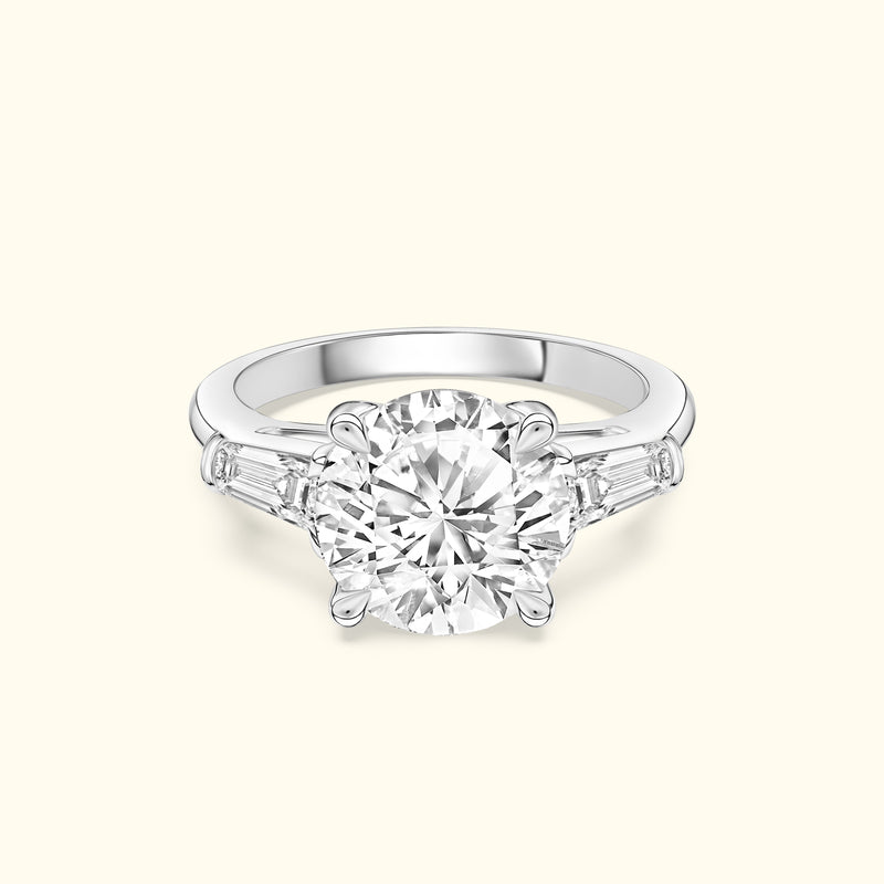 Three-stone engagement ring featuring a large round diamond center and tapered side stones.