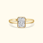 A gold ring featuring a large rectangular diamond in a simple, elegant setting.