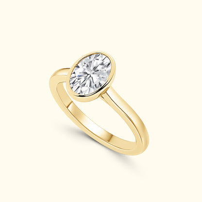 Gold ring featuring an oval, sparkling diamond centerpiece on a smooth band.