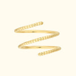 Spiral gold ring with textured design, set against a light background.