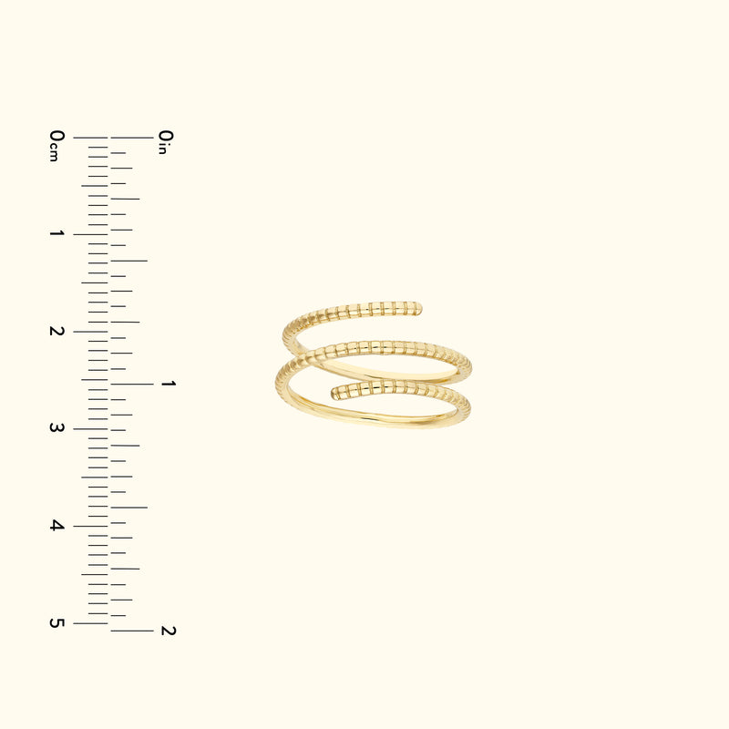Gold spiral ring displayed next to a ruler for size reference.