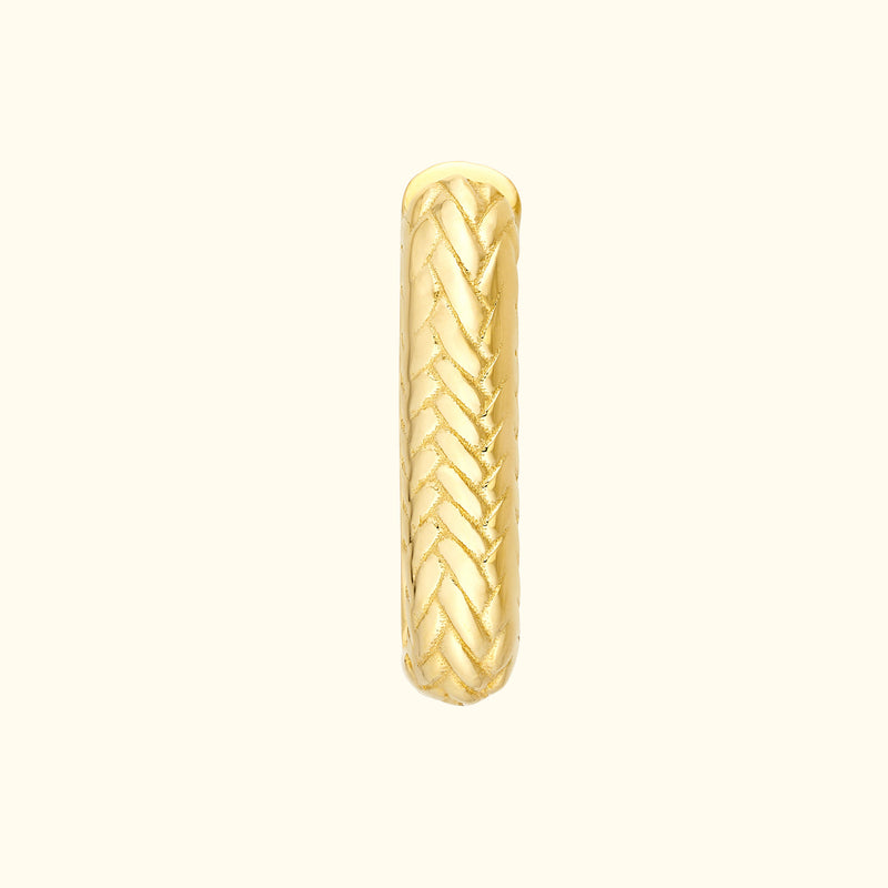 Golden braided ring with a textured surface, reflecting light elegantly.