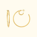 Two gold hoop earrings, one smaller and the other larger, set against a light background.