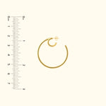 Gold hoop earring displayed next to a ruler for size reference.