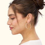 Gold hoop earrings worn by a woman with a bun hairstyle, showing her profile.