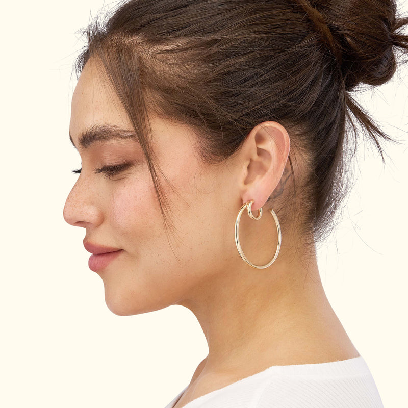 Gold hoop earrings worn by a woman with a bun hairstyle, showing her profile.
