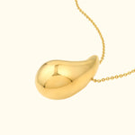 Shiny gold pendant on a delicate chain against a light background.