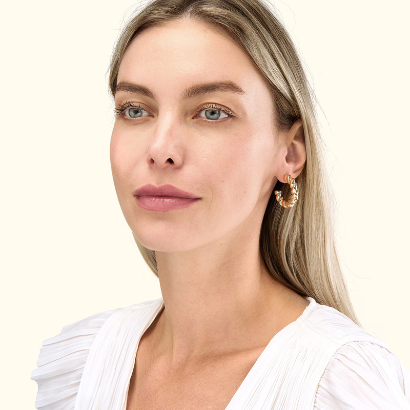 A woman with long, blonde hair wears a large, gold hoop earring.