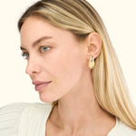 Gold teardrop earrings worn by a woman with long, straight blonde hair.