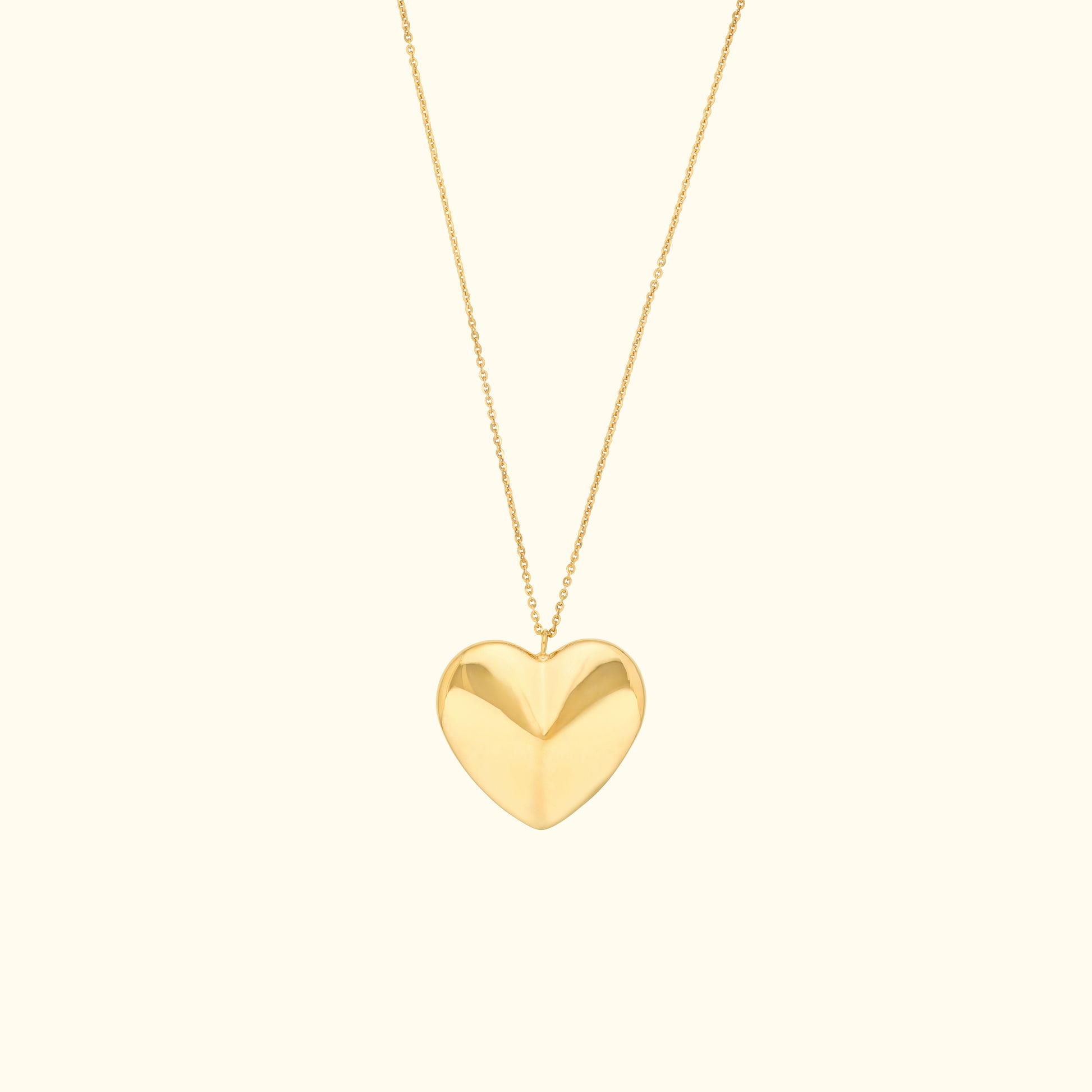 Gold heart pendant necklace on a delicate chain against a light background.