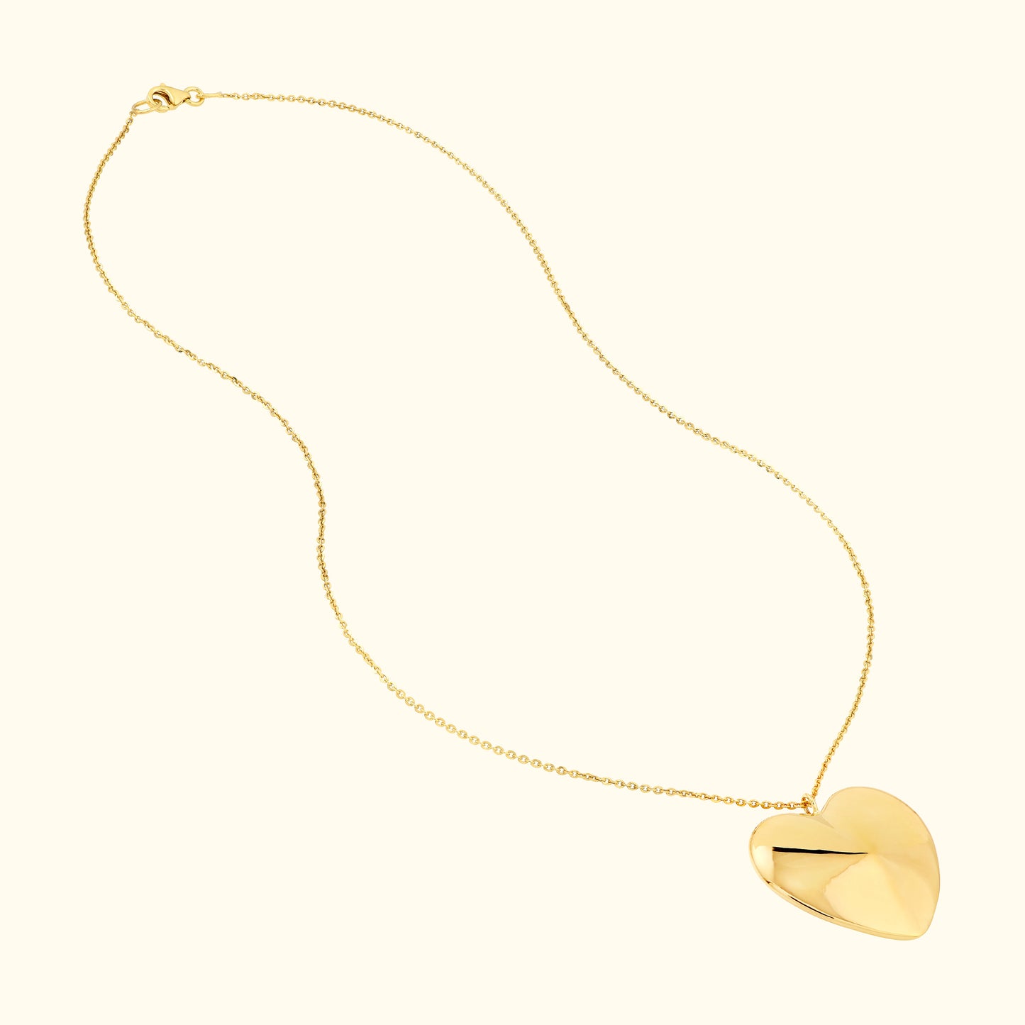 Delicate gold necklace featuring a large, polished heart pendant.