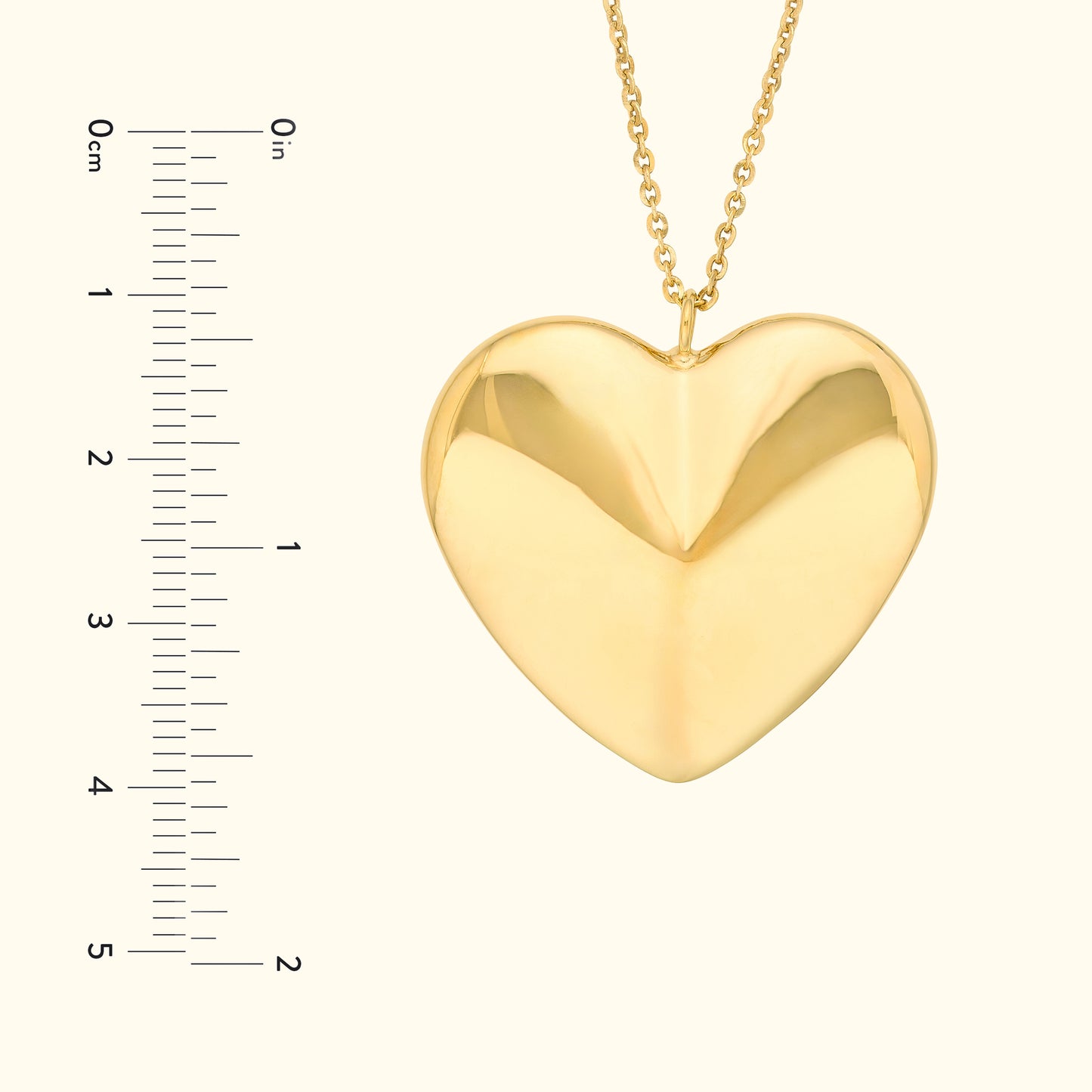 Golden heart-shaped pendant on a chain, with a ruler for size reference.