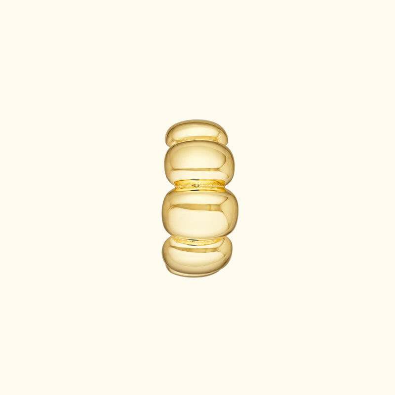 Smooth, stacked gold ring with rounded shapes against a light background.
