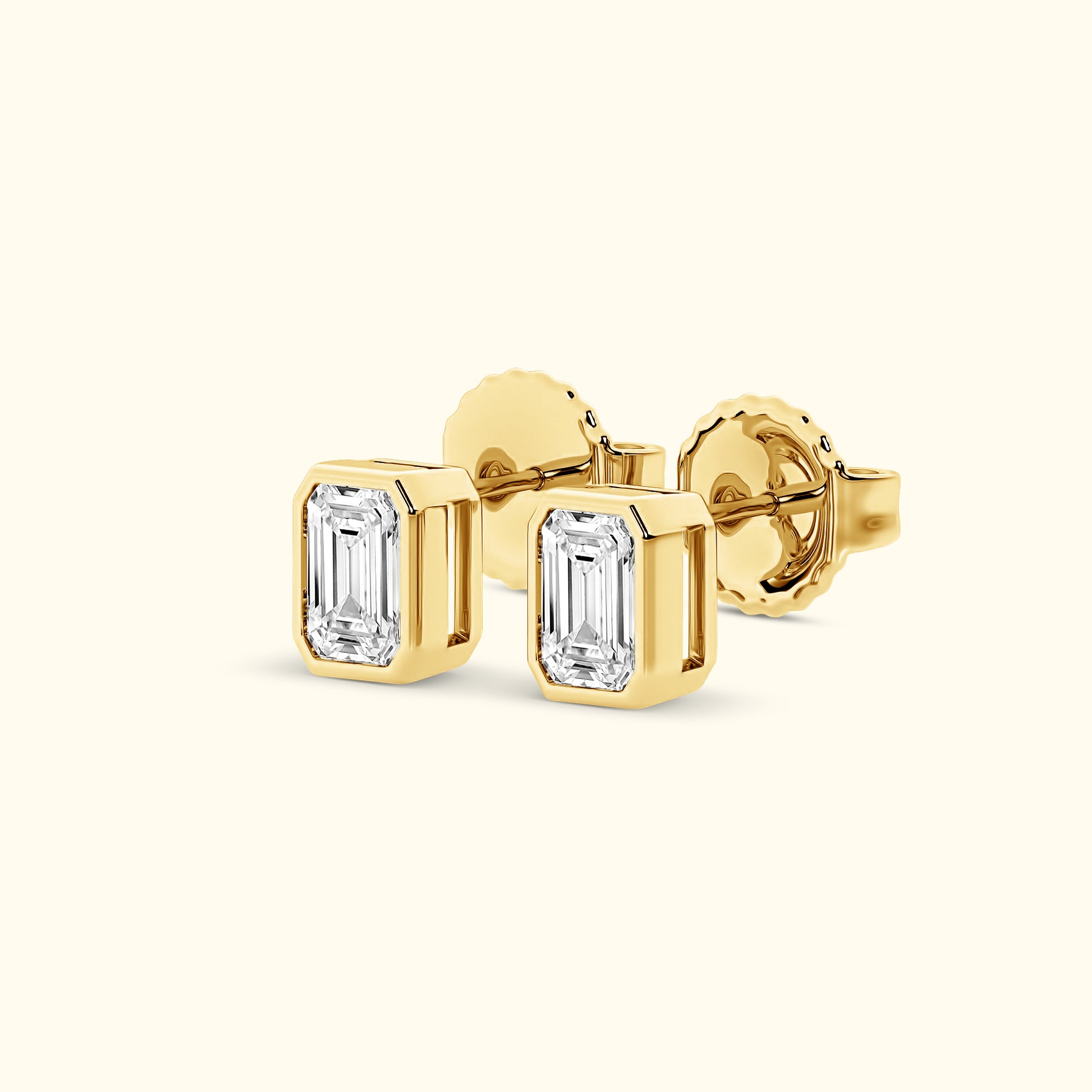 Emerald-cut diamond stud earrings set in yellow gold.