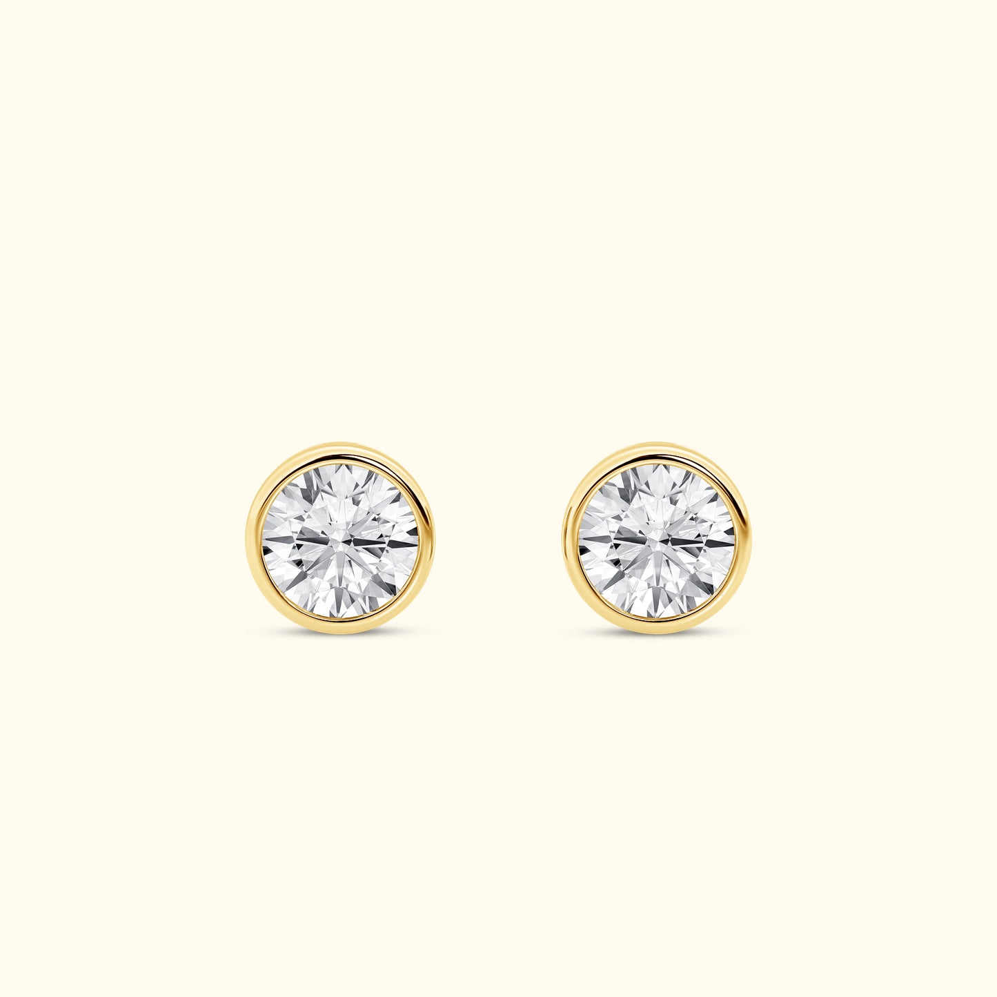 Gold stud earrings with round, sparkling diamond-like stones.