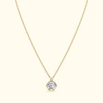 Gold necklace with a hexagonal diamond pendant on a light background.