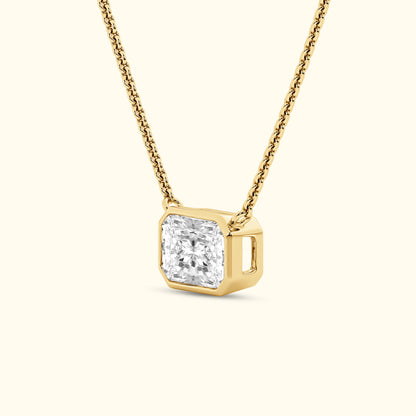 Square diamond pendant on a delicate golden chain against a light background.