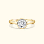 Gold ring featuring a large, round diamond set in a simple bezel.