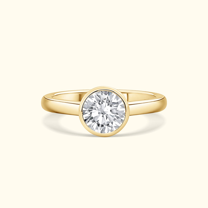 Gold ring featuring a large, round diamond set in a simple bezel.