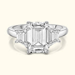 Elegant three-stone ring featuring a central emerald-cut diamond flanked by smaller diamonds.